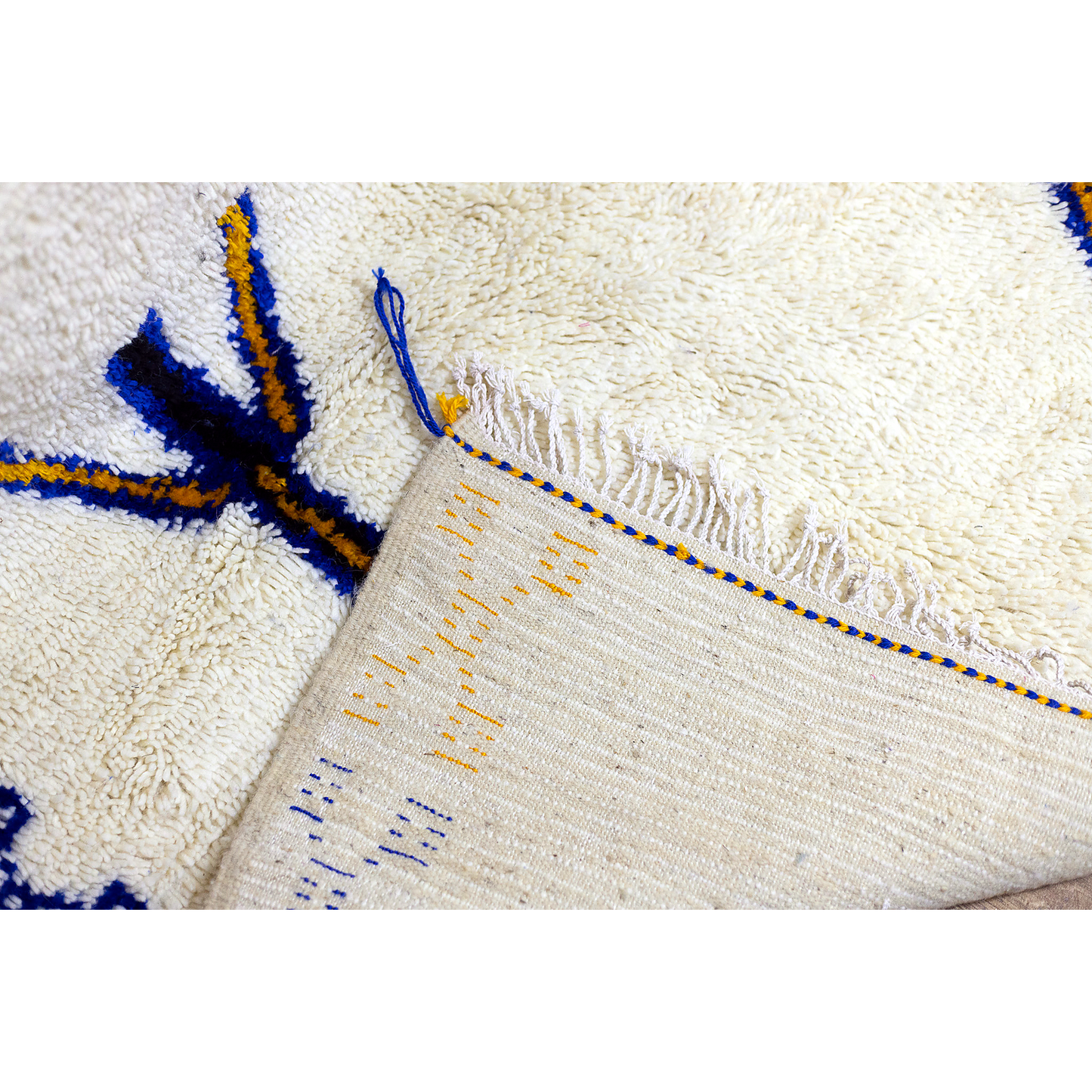 Border and motif detail of Moroccan Azilal rug with saffron and indigo symbols.