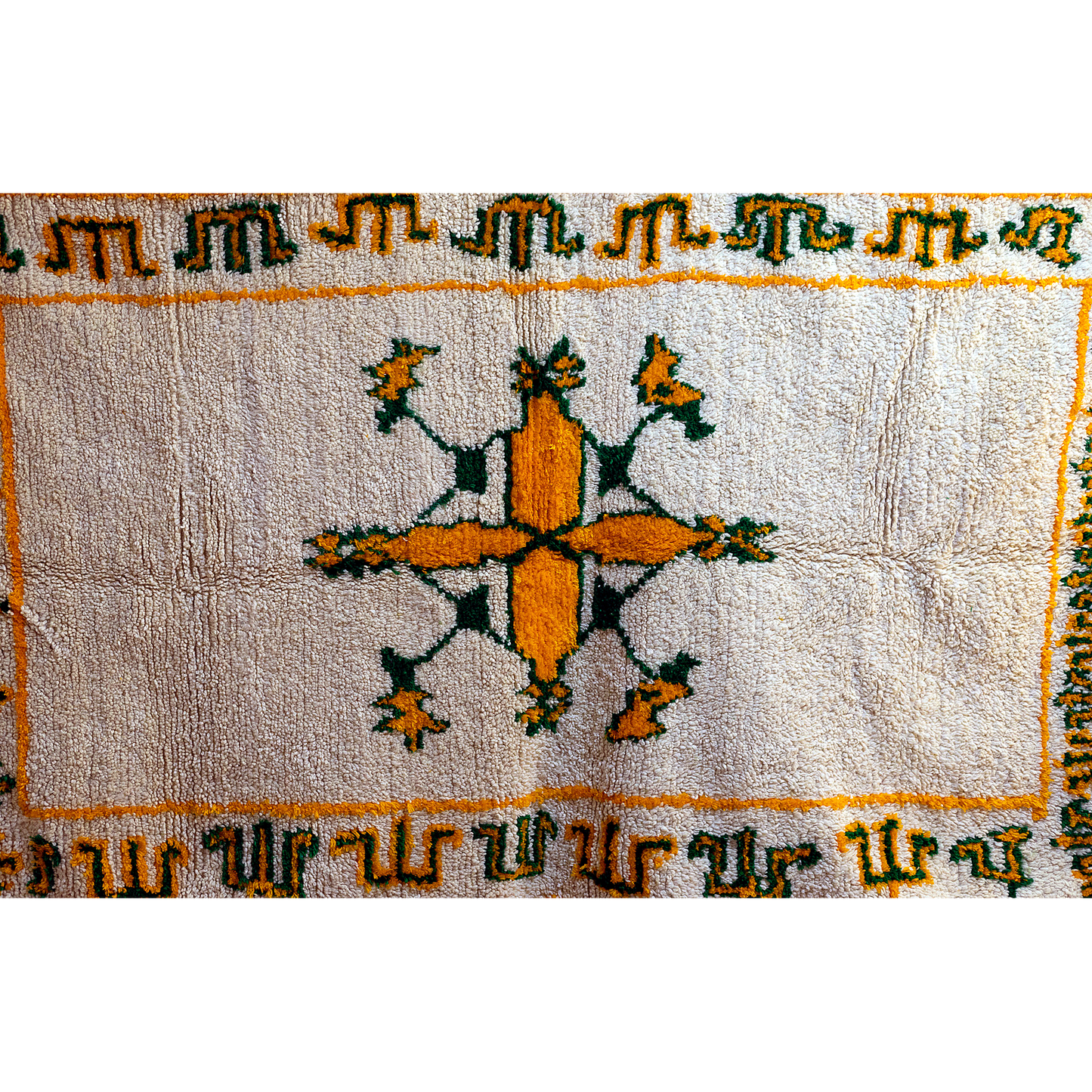 Border detail with green Amazigh designs on ivory Moroccan rug.