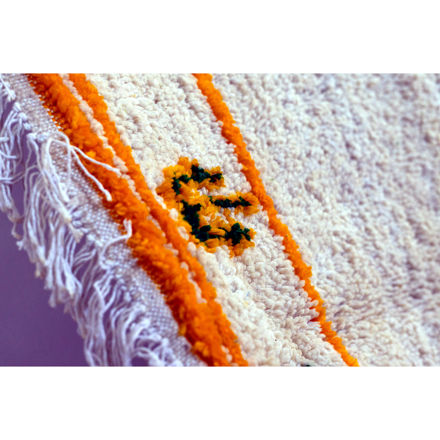 Corner of Azilal rug with fringe and golden-green geometric border.